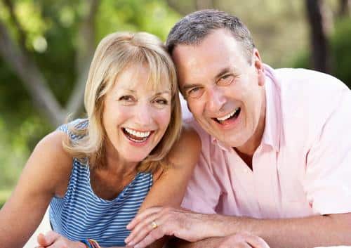 Smiling couple outdoors in casual clothing, posing together in natural daylight setting.