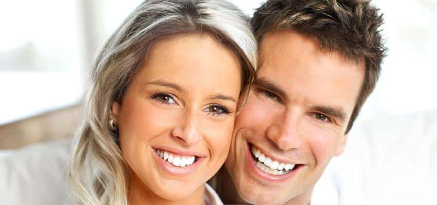 Smiling man and woman posing together in bright, modern dental office setting.