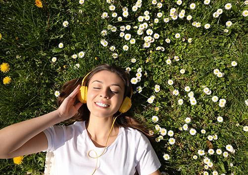 Woman smiling at camera against floral wall backdrop with white and yellow flowers.