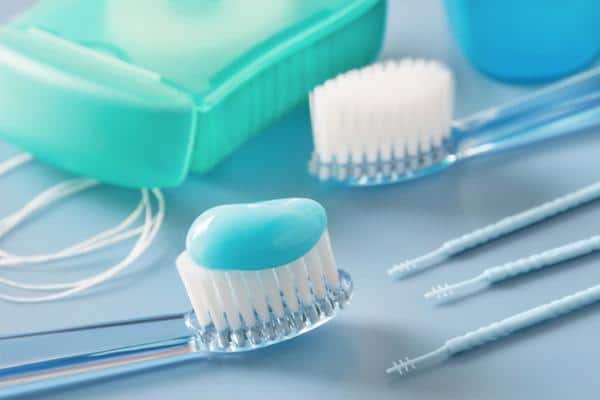 Dental care products including toothbrushes, floss, and mouthwash arranged on reflective surface