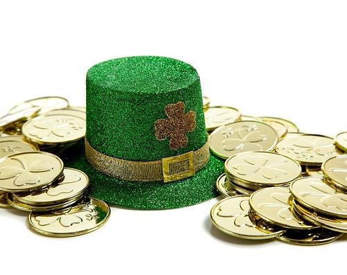 Green leprechaun hat surrounded by gold coins on white background