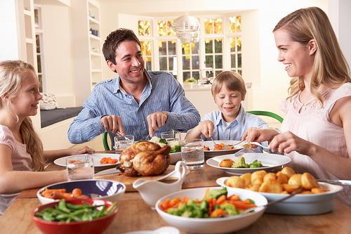 Family of four enjoying healthy meal together at dining table at home.