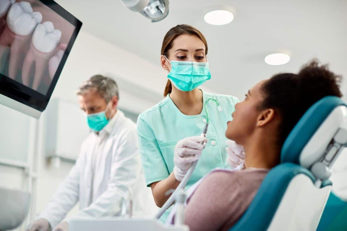Dentist and assistant examining patient in dental chair at modern clinic.