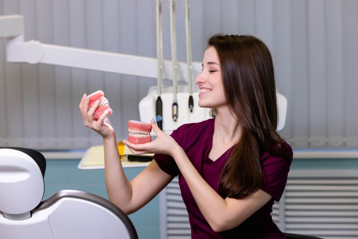Woman holding dental model demonstrating teeth structure in modern dental office setting.