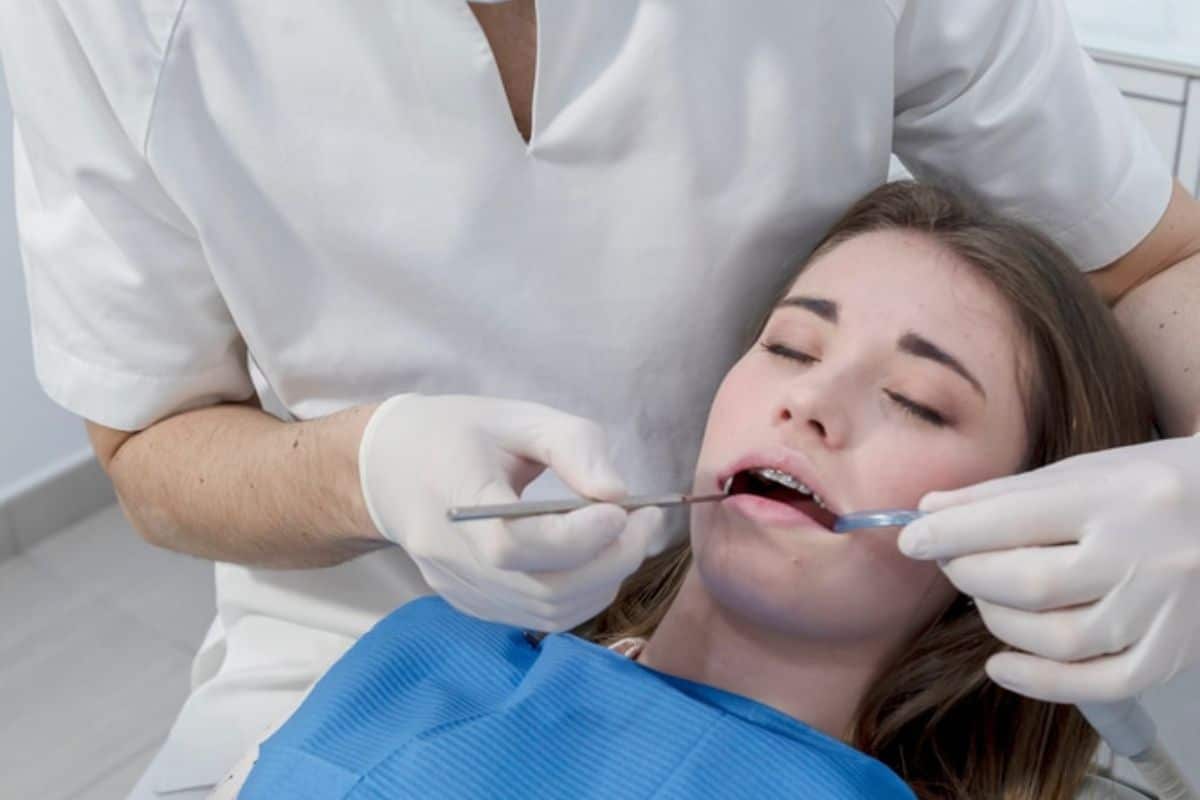Dentist examining patient's teeth during dental checkup in clinical setting.