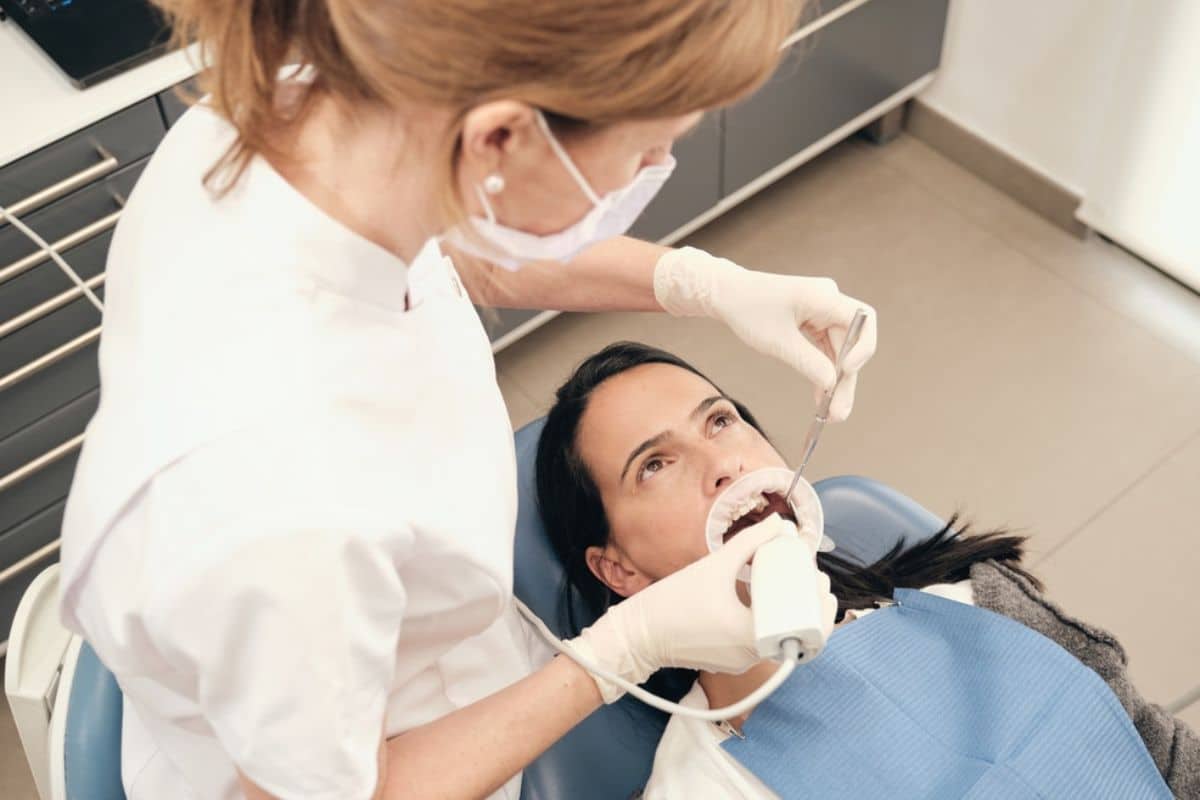 Dentist examining patient's teeth in dental office chair during checkup